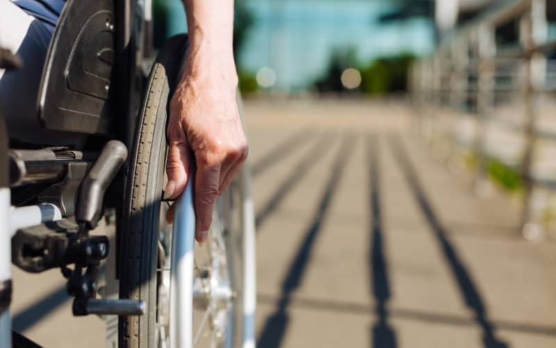 diversidad-funcional-discapacidad-1 Primer plano de una mano manejando una silla de ruedas, como símbolo respresentativo de la disyuntiva entre diversidad funcional o discapacidad