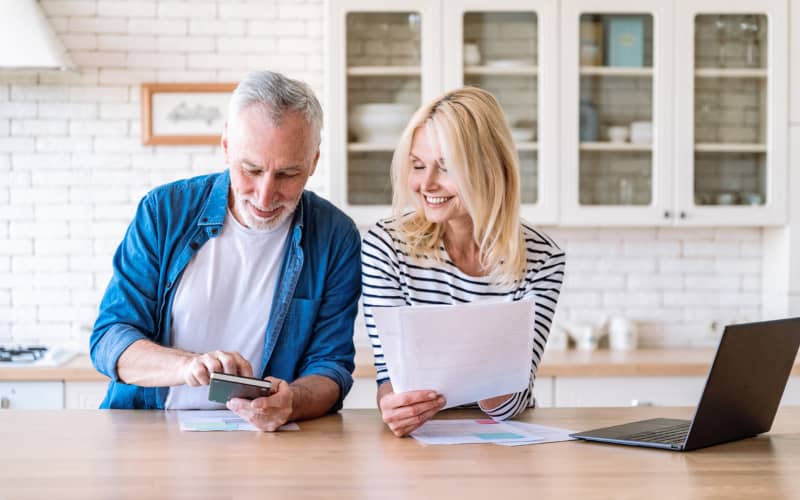 Pareja madura revisando documentación en la cocina de casa, en representación de la revisión que debemos hacer antes de contratar un seguro con copago o sin copago
