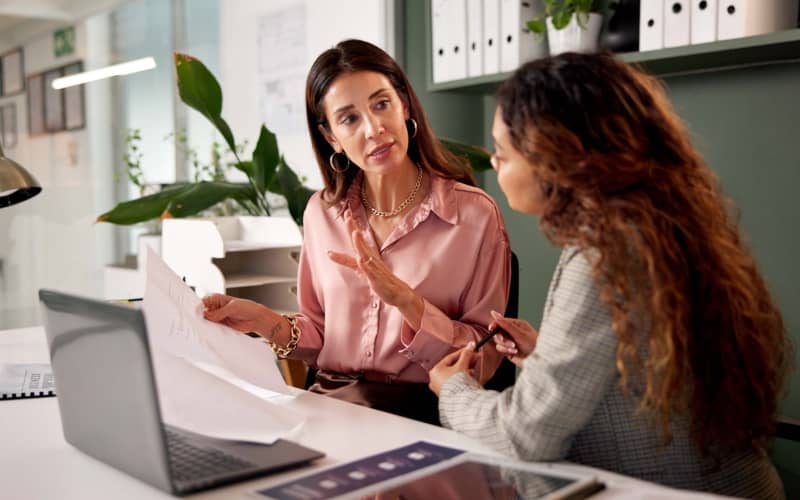 Asesora explicando las condiciones de un seguro de salud sin copago a una clienta en una oficina
