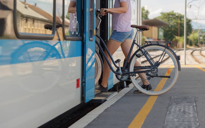 Bicicleta y tranvía en una calle urbana como opciones de transporte sostenible para reducir emisiones de CO₂, en representación de la huella de carbono personal