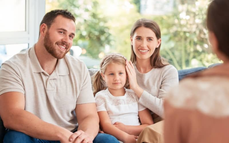 Familia sonriente con un hija pequeña recibiendo asesoramiento sobre seguro de salud sin copago
