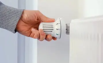 como-purgar-los-radiadores-00.jpg Mano girando la válvula termostática de un radiador, paso previo habitual en el proceso de cómo purgar los radiadores.