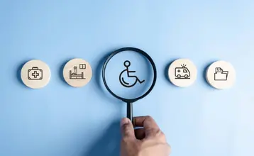 Cuatro iconos en representación de la accesibilidad cognitiva con uno destacado en el centro con una lupa, correspondiente al símbolo de persona con discapacidad.