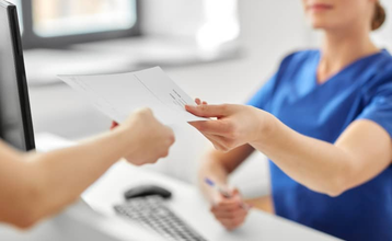 Profesional sanitaria entregando documentación médica a paciente en recepción de clínica